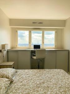 Vue panoramique sur Paris : Sublime appartement au centre de Courbevoie في كوربفوا: غرفة نوم بسرير ومكتب ونوافذ