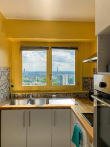 Vue panoramique sur Paris : Sublime appartement au centre de Courbevoie في كوربفوا: مطبخ مع حوض ونوافذ