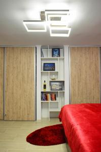 a bedroom with a red bed and a book shelf at Lovely 2 bedroom apartment in the City Centre of Oradea in Oradea