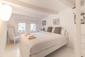 a white bedroom with a large white bed and a chair at Precioso Apartamento en Mercat Sant Antoni in Barcelona