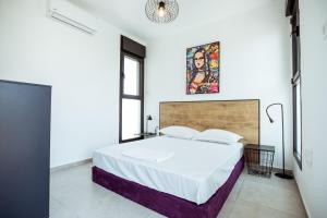 a bedroom with a large bed in a white room at הרצל בוטיק מבית דומוס - Herzl Boutique Apartments by Domus in Beer Sheva