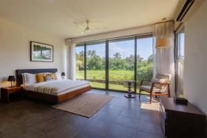 a bedroom with a bed and a large window at StayVista at Bella Aries in Calangute