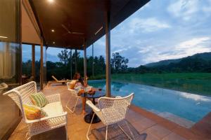 two people sitting on the patio of a house with a pool at StayVista at Bella Aries in Calangute