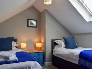 a attic bedroom with two beds and two lamps at Heather Lea in Summer Bridge