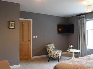 a bedroom with a bed and a chair and a tv at Heather Lea in Summer Bridge
