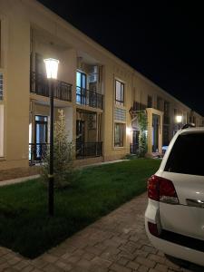 un coche aparcado delante de un edificio por la noche en KERUEN SARAY APARTMENTS 6/2 en Türkistan