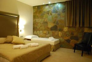 a hotel room with two beds and a rock wall at Hotel Konaki in Arnaia