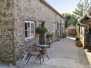 a table and chairs outside of a brick building at Grace Cottage in Umberleigh Bridge