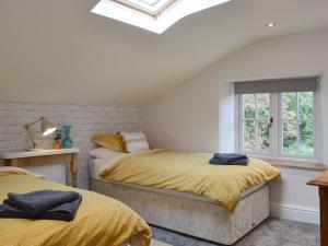 a bedroom with two beds with yellow sheets and a window at Grace Cottage in Umberleigh Bridge