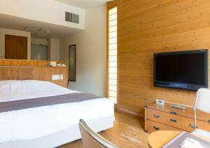 a bedroom with a bed and a flat screen tv at Yatsugatake Hotel Fuuka in Hokuto