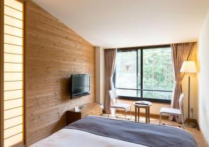 a hotel room with a bed and a tv at Yatsugatake Hotel Fuuka in Hokuto