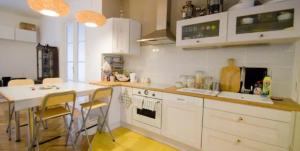 ブダペストにあるRadnoti design Studioの白いキャビネット、テーブルと椅子付きのキッチンが備わります。