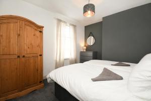 a bedroom with a large white bed and a wooden cabinet at Cottage Style 3 bedroom House - Close to City centre & The Peaks in Chesterfield