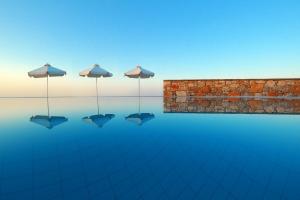 three umbrellas in the water in front of a wall at Belvedere Apartments in Chora Folegandros