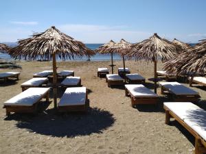 a group of beach chairs and umbrellas on a beach at Nostos Beachfront Apartments & Studios in Agios Ioannis