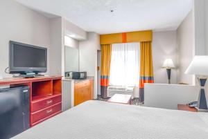 a hotel room with a bed and a flat screen tv at Days Inn & Suites by Wyndham Prattville-Montgomery in Prattville