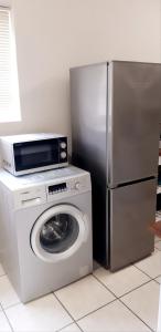 a kitchen with a washing machine and a refrigerator at Zeezicht Holiday Guest Unit in Franskraal