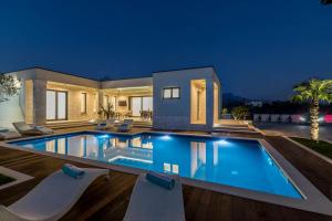 una casa con piscina por la noche en Maglica Exclusive Residence, en Kaštela