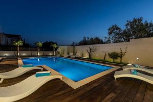 una piscina en un patio trasero con terraza de madera en Maglica Exclusive Residence, en Kaštela
