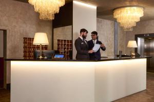 two men standing at a counter in a library at Best Western Park Hotel Continental in San Donà di Piave