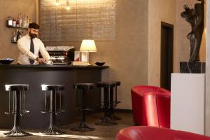 Un uomo in piedi dietro un bancone in un bar con sgabelli. di Best Western Park Hotel Continental a San Donà di Piave