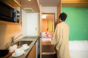 a man standing in a kitchen looking at a girl at Gozan Hotel & Serviced Apartment Higashiyama Sanjo in Kyoto