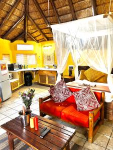 a room with a bed and a table and a kitchen at Manzini Chalets in Marloth Park