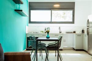 貝爾謝巴的住宿－הרצל בוטיק מבית דומוס - Herzl Boutique Apartments by Domus，厨房里设有一张桌子和椅子,拥有蓝色的墙壁
