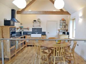 a kitchen with a wooden table and wooden chairs at Love Barn in Darlington