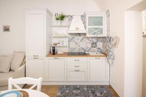 a kitchen with white cabinets and a living room at VICOLO MURO in Molfetta