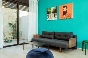 a living room with a couch and a blue wall at הרצל בוטיק מבית דומוס - Herzl Boutique Apartments by Domus in Beer Sheva