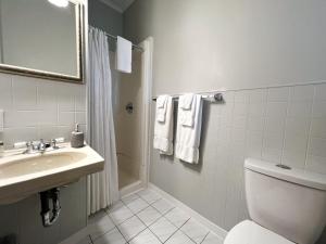 een badkamer met een wastafel, een toilet en een spiegel bij Inn at the Falls in Bracebridge