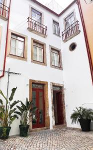un bâtiment blanc avec des portes rouges et des plantes en pot dans l'établissement Casa do Postal @ Casas do Pátio (5), à Coimbra