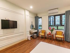 a living room with a television and a table and chairs at Madelise Max Hotel in Hanoi