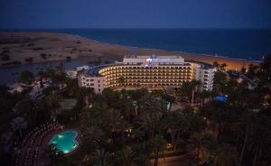 um hotel na praia com palmeiras e o oceano em Seaside Palm Beach em Maspalomas