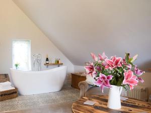 baño con bañera y jarrón de flores rosas en The Garden Retreat, en Marbury