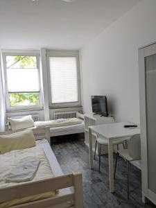 a white room with a bed and a table and two windows at PM-Rooms in Munich