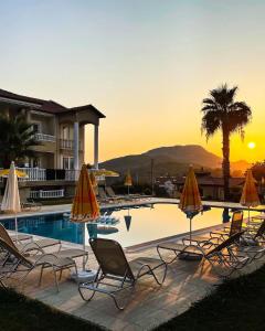 un grupo de sillas y sombrillas junto a una piscina en Gold Lion Hotel, en Ölüdeniz