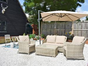 a patio with a table and chairs and an umbrella at The Coach House in Peldon