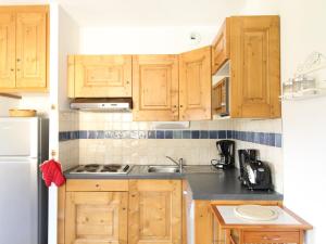 een keuken met houten kasten, een wastafel en een koelkast bij Appartement Aussois, 3 pièces, 6 personnes - FR-1-508-30 in Aussois
