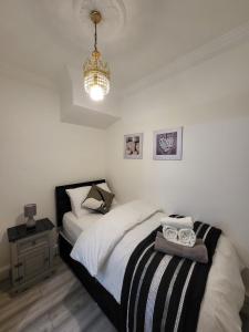 a bedroom with a black and white bed and a chandelier at Eastend Apartments in London