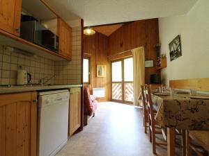 a kitchen with wooden cabinets and a table with a counter top at Appartement Lanslevillard, 2 pièces, 6 personnes - FR-1-508-112 in Lanslevillard