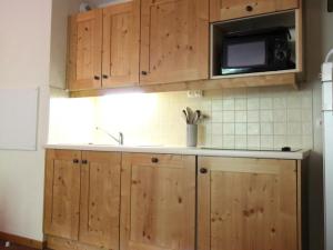 a kitchen with wooden cabinets and a microwave at Appartement Lanslebourg-Mont-Cenis, 2 pièces, 4 personnes - FR-1-508-132 in Lanslebourg-Mont-Cenis