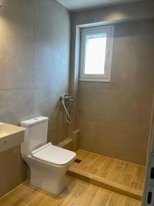 a bathroom with a white toilet and a window at Campana’s Apartment in Argostoli