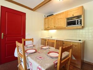 a kitchen with a table with chairs and a red door at Appartement Lanslebourg-Mont-Cenis, 2 pièces, 4 personnes - FR-1-508-186 in Lanslebourg-Mont-Cenis