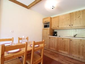 a kitchen with wooden cabinets and a table and chairs at Appartement Lanslebourg-Mont-Cenis, 2 pièces, 4 personnes - FR-1-508-143 in Lanslebourg-Mont-Cenis