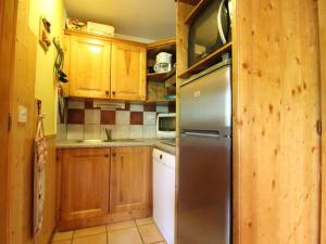 a kitchen with wooden cabinets and a stainless steel refrigerator at Appartement cosy 6 personnes proche des pistes à Val Cenis avec balcon, WiFi et parking sous-sol - FR-1-508-214 in Lanslevillard