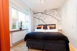 a bedroom with a bed and a tree mural at ApartDirect Solna in Solna