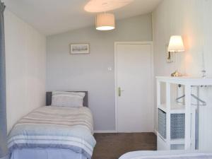 ein kleines Schlafzimmer mit einem Bett und einer weißen Wand in der Unterkunft Coles Retreat in Anderby