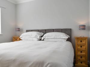 a white bed with two pillows and two night stands at Pier View in Gorleston-on-Sea